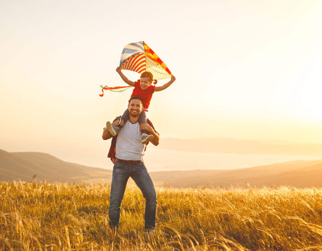 gelukkig gezin vader en kind dochter lopen met een vlieger op weide